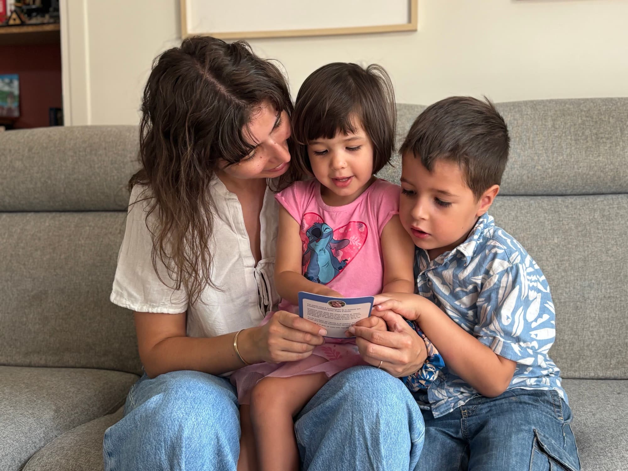 Une maman et ses deux enfants consultent ensemble une carte souvenir Zaza.